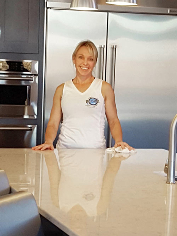 Smiling woman cleaning kitchen counters.
